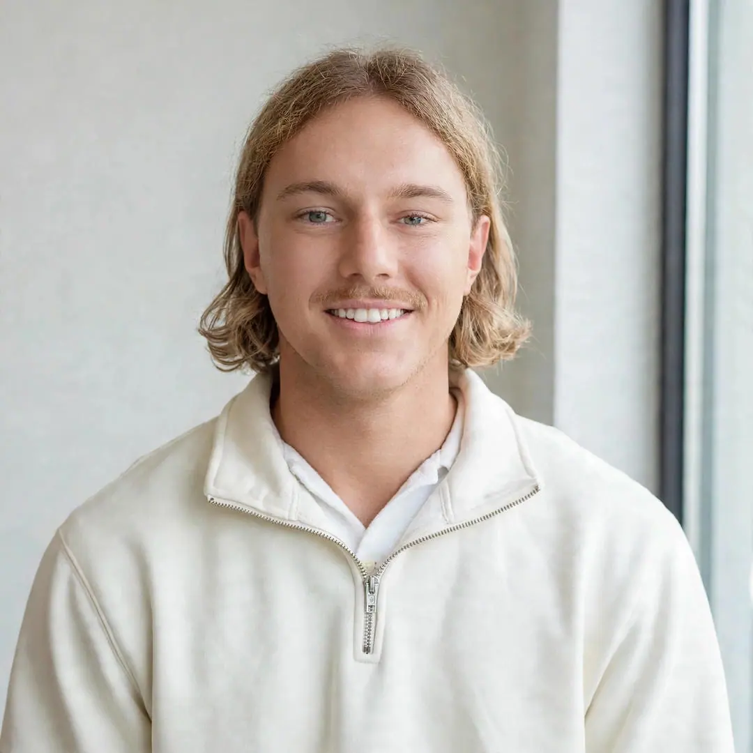 Anthony Bowen, co-founder of Best Invest, smiling in a cream quarter zip by a window